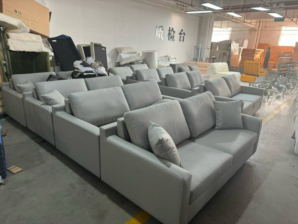 Light-grey sofa beds staged together near a workshop quality-inspection area