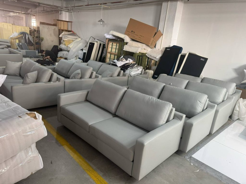 Light-grey upholstered sofa beds arranged in a workshop production row
