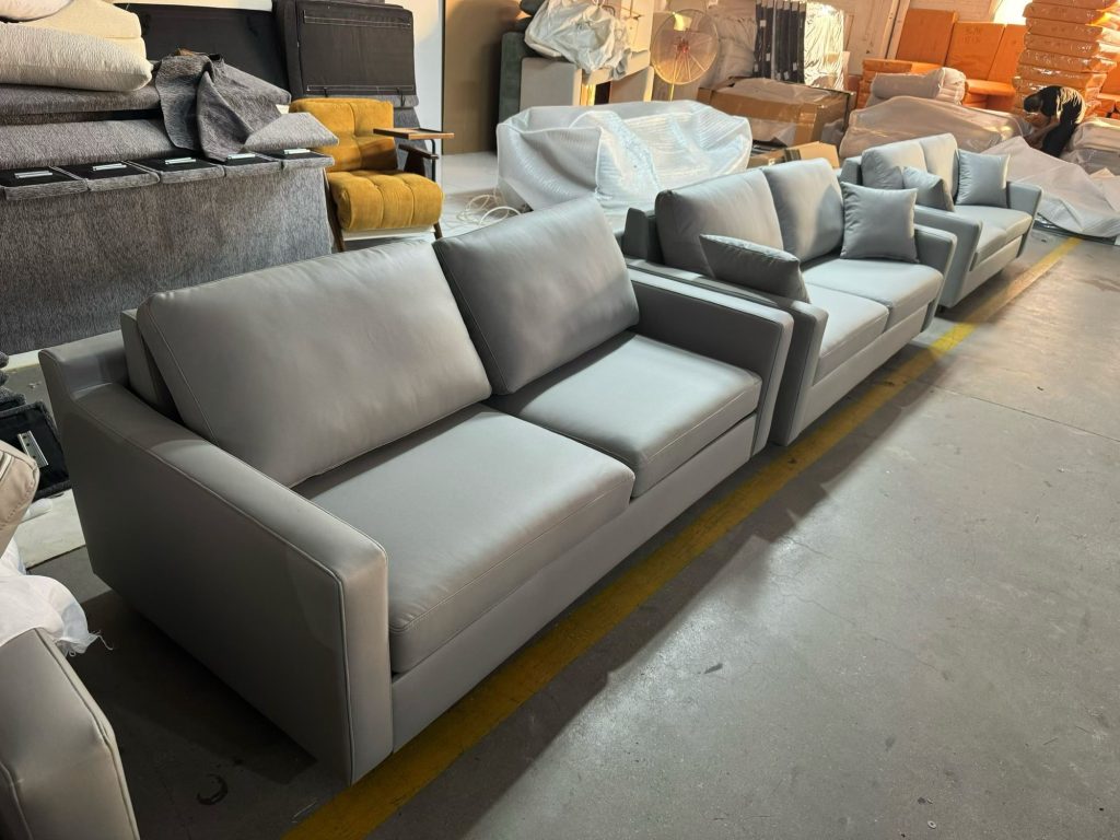 A lineup of light-grey sofa beds shown from the side in the workshop