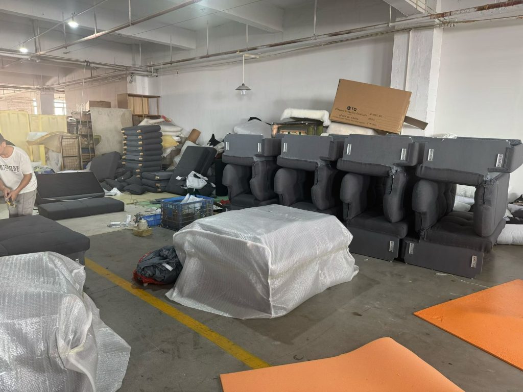 Workshop area with sofa-bed components and upholstered units during assembly