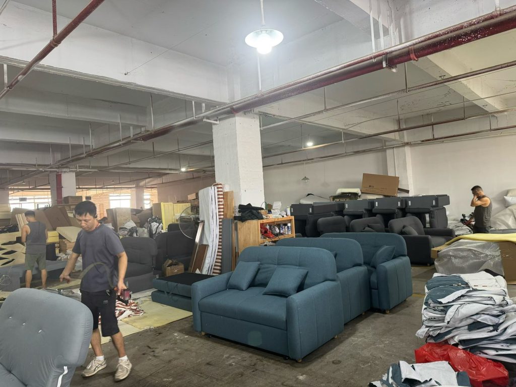 Staff working among sofa-bed units during workshop production