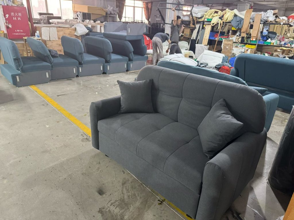 Dark-grey sofa bed with button-tufted upholstery displayed in the workshop