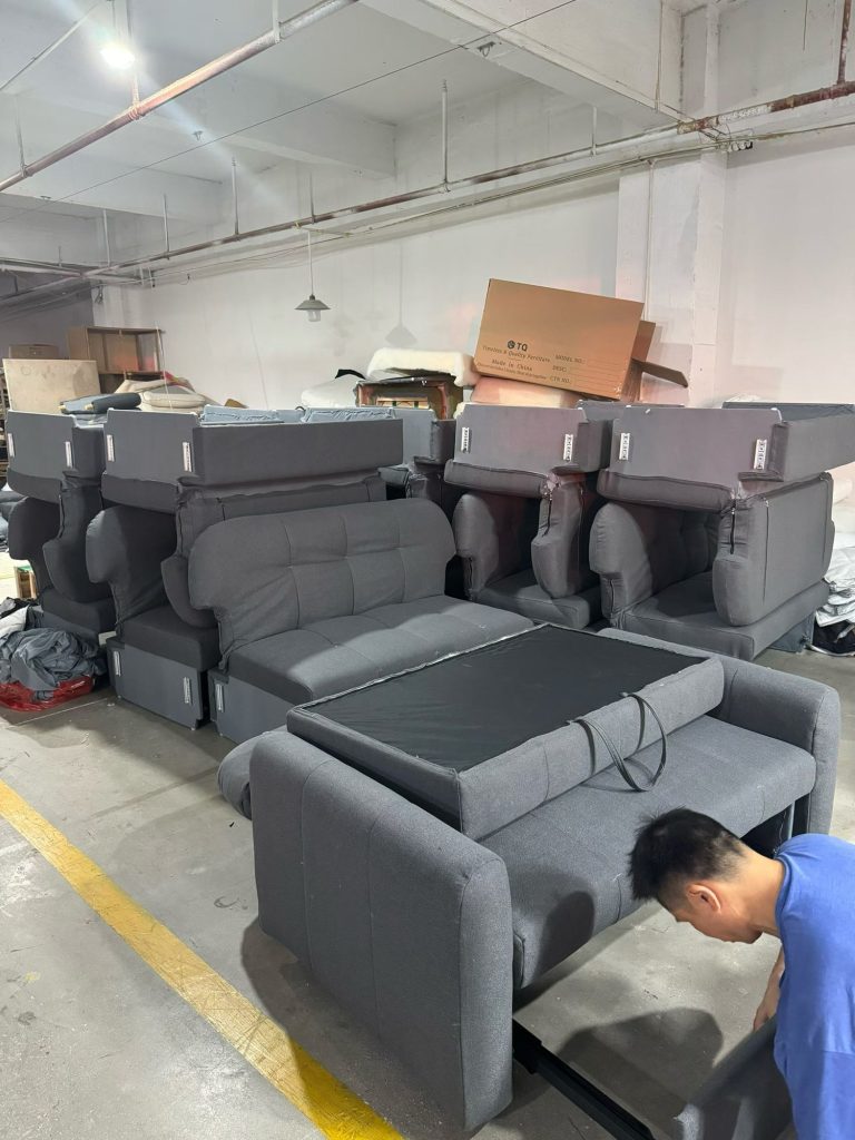 Workshop staff checking an extended sofa-bed frame and seat assembly